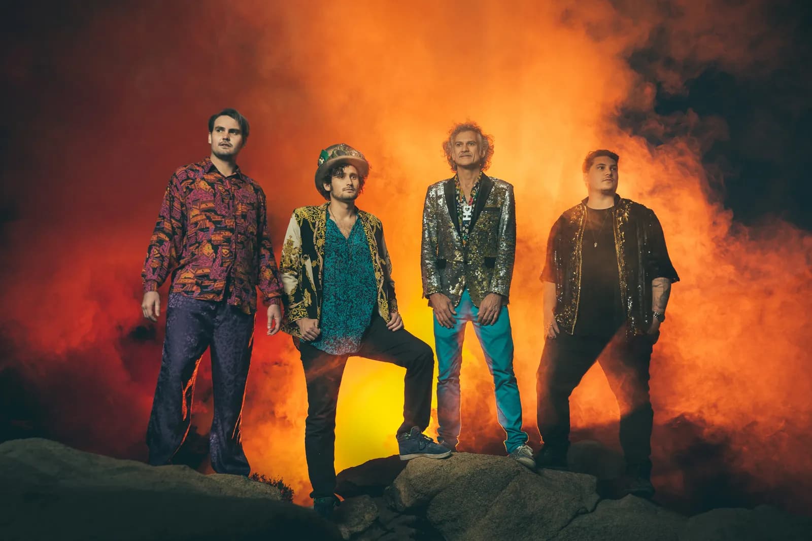 Four musicians standing in orange smoke