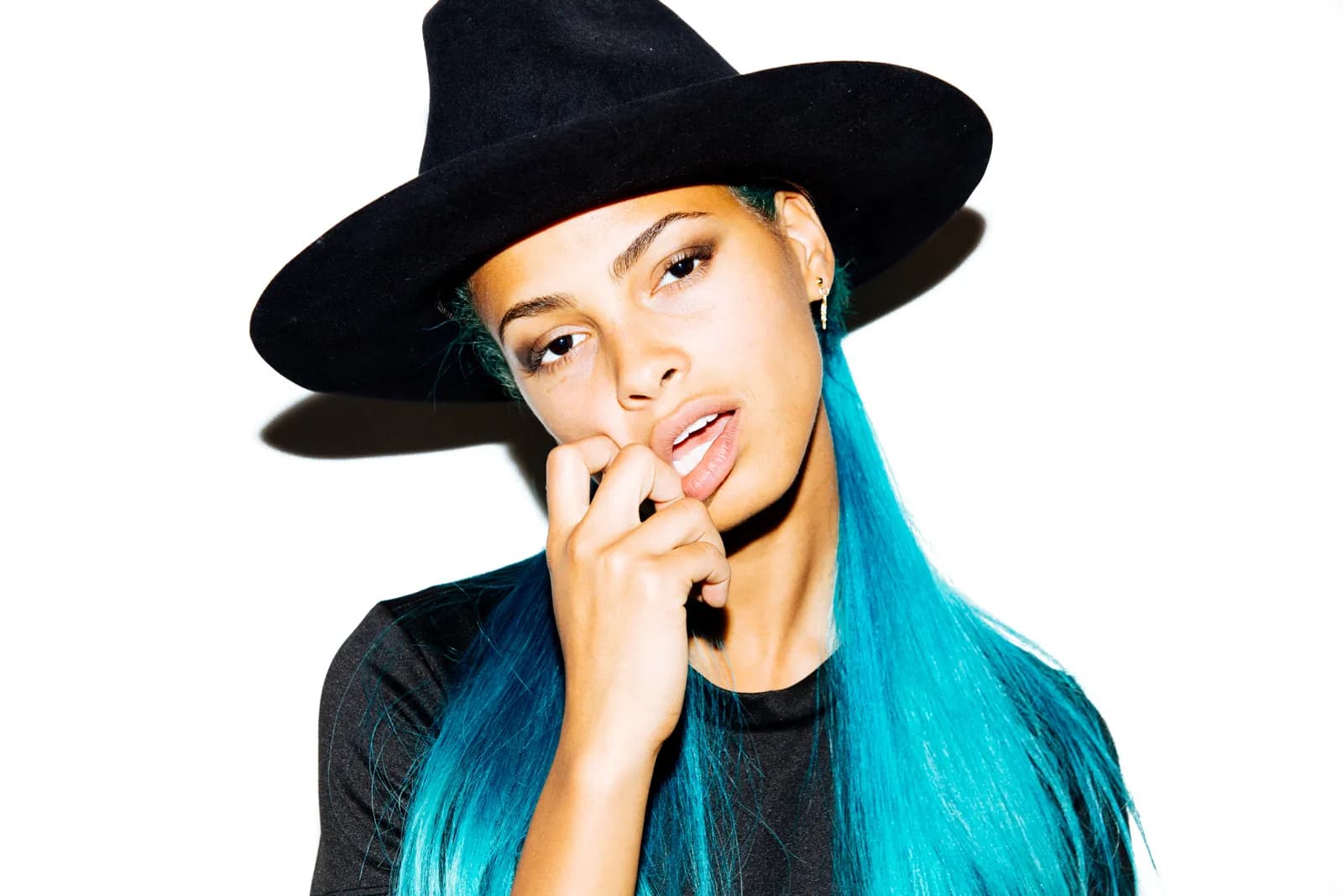 A woman with blue hair and a wide black hat on white
