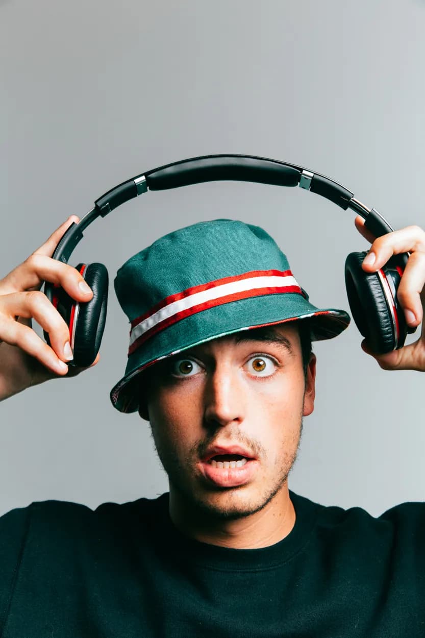 A man in a bucket hat pulling on headphones