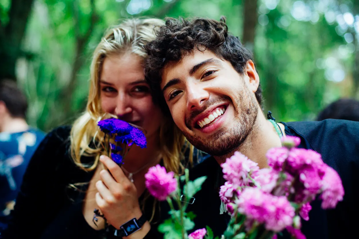 A laughing couple holding purple flowers