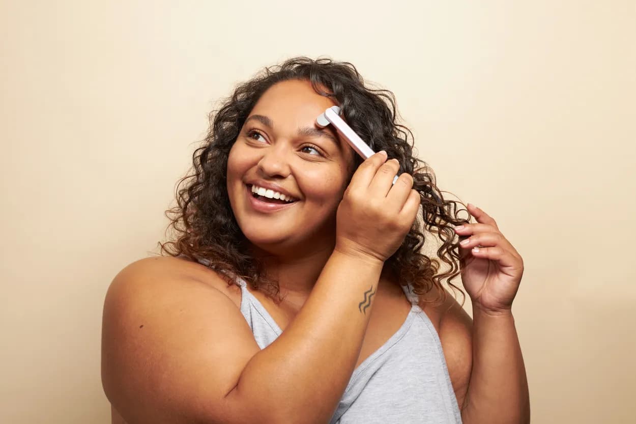 A woman with curly hair laughing in natural light